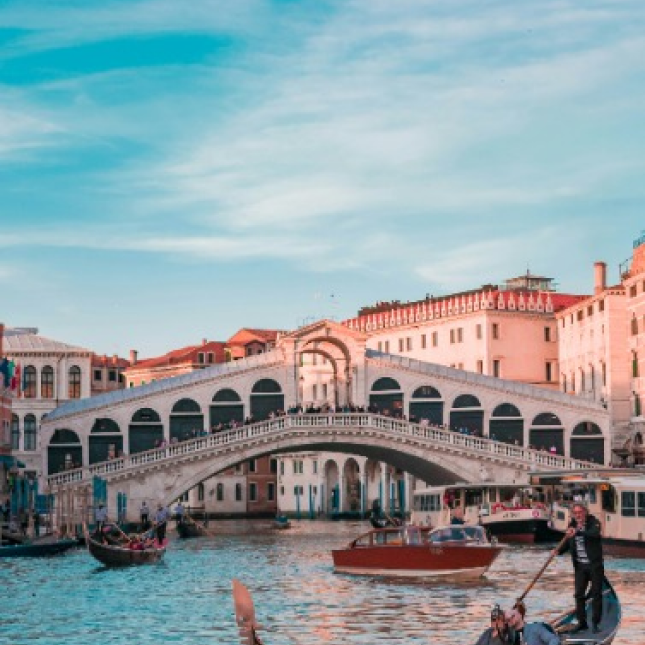 A Ponte de Rialto em Veneza cruzando o canal com barcos passando por baixo.